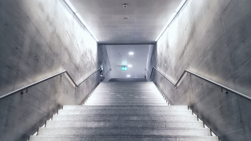 A photograph of a well-lit, concrete stairway.